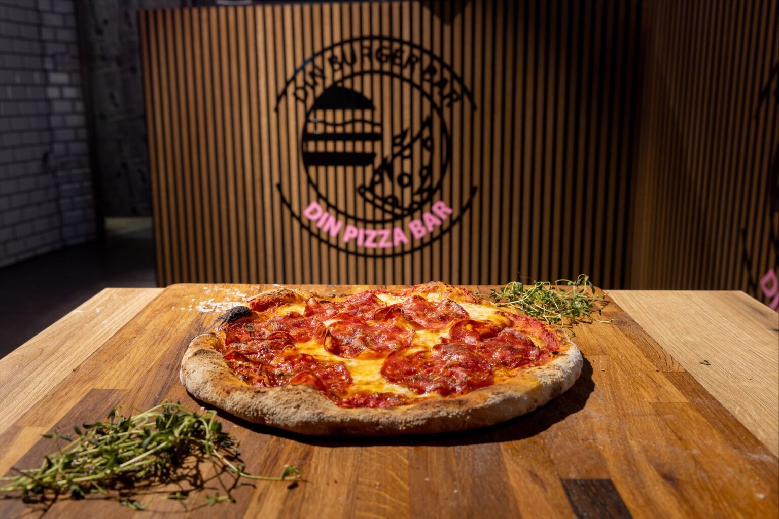 Pepperoni pizza på træbord i restaurant